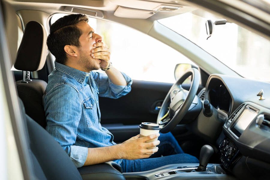 man yawning in car during commute