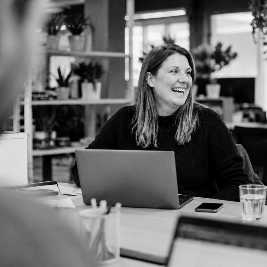 Woman laughing during a meeting at a table with a laptop