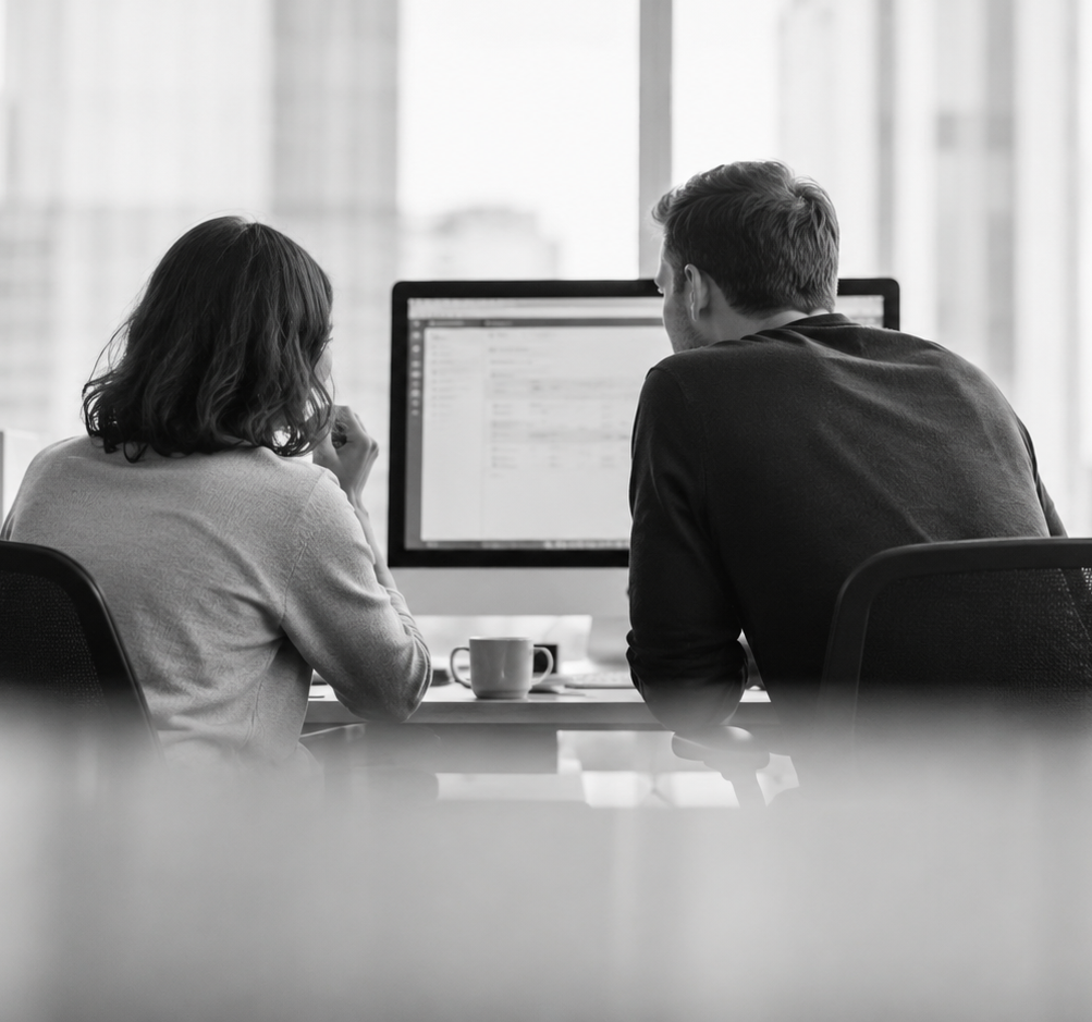Two professionals reviewing data on a shared screen, representing AI governance and cost oversight in the workplace
