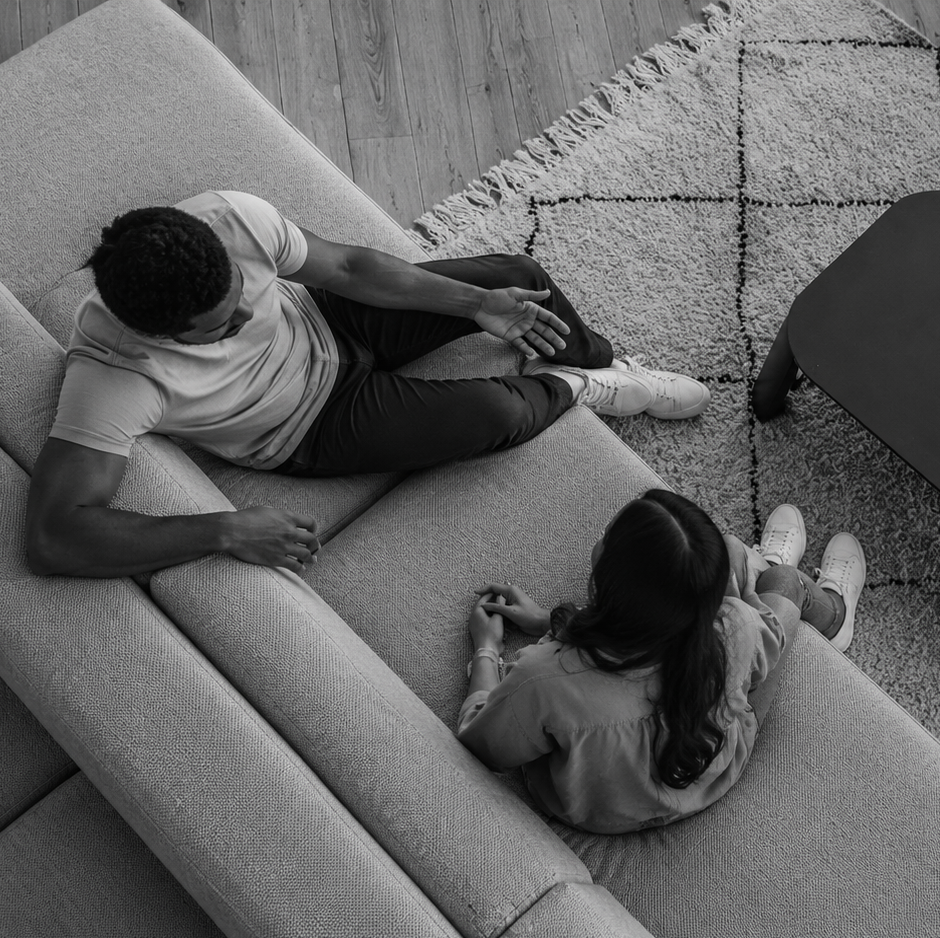 Overhead view of a man relaxing on a couch with a coworker sitting nearby