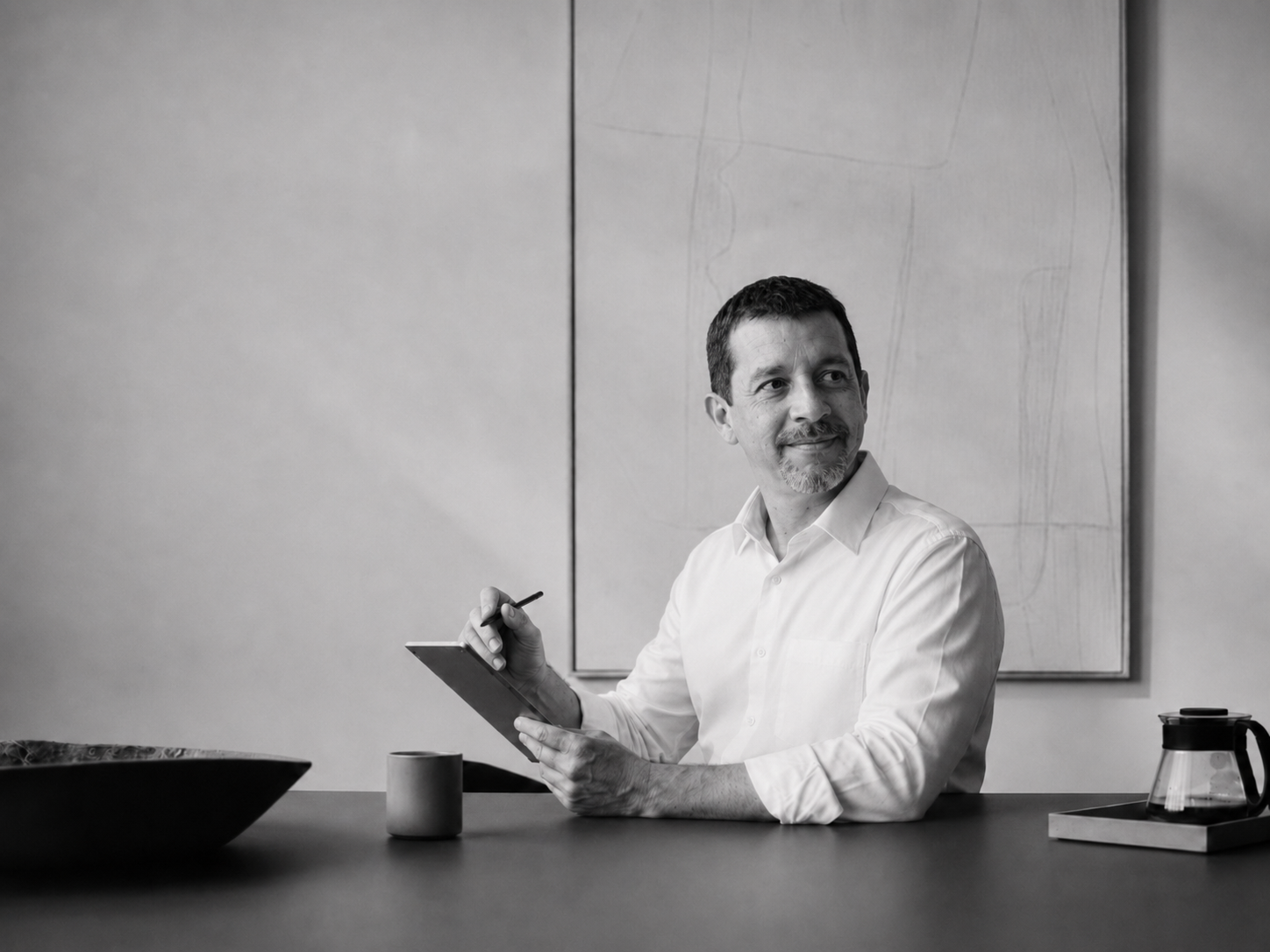 IncWorx Microsoft consultant smiling at client, sitting at a table, holding an tablet and tablet stylus.