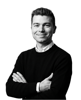IncWorx consultant, Riley, posed arms crossed for his headshot. He is wearing a black sweater over a white collared shirt.