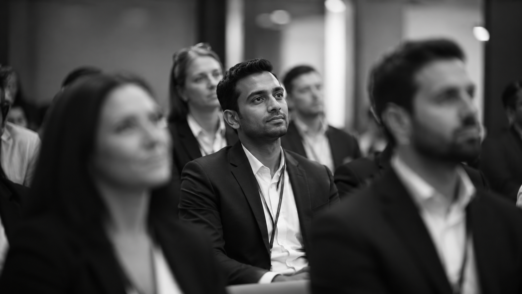 Black-and-white image of business professionals attending a conference or training session.